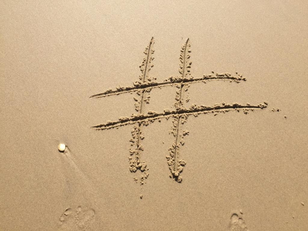 Image on a beach showing a hashtag sign.